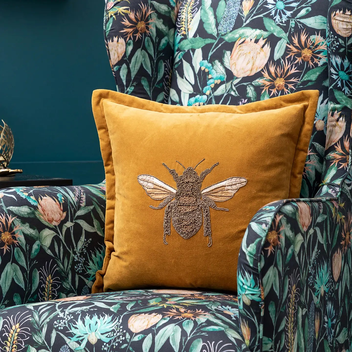 Mustard yellow pillow with bee design on a floral-patterned chair