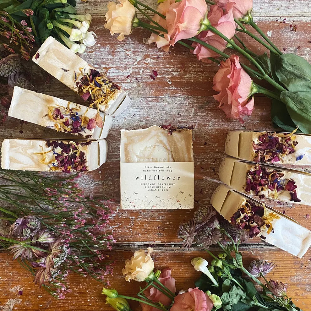 Luxury wildflower soap bars on a wooden surface surrounded by fresh flowers