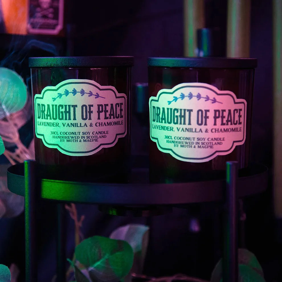 Two candles labeled 'Draught of Peace' with a colorful label design on a dark background.