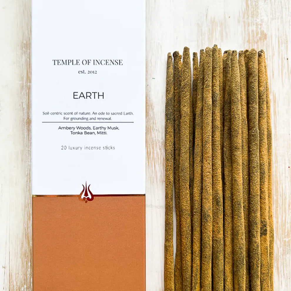 Incense sticks with packaging labeled 'Temple of Incense' 'Earth' on a light wooden background