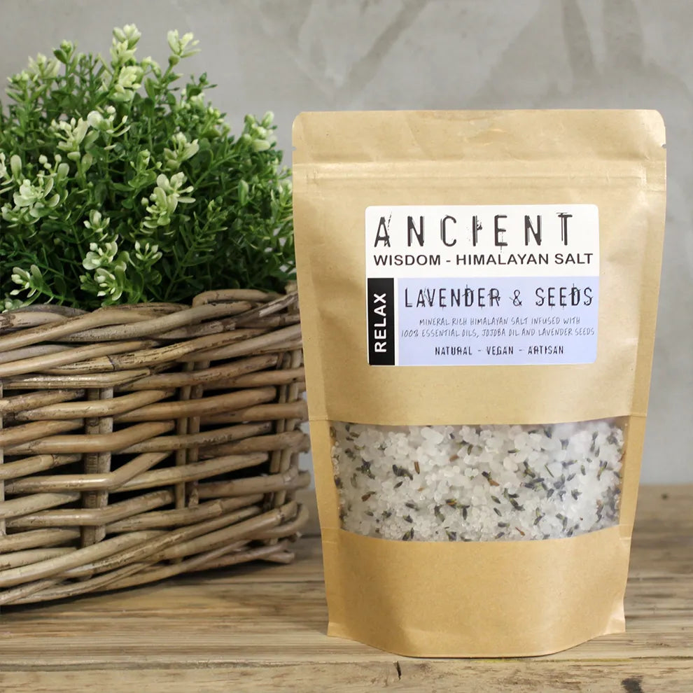Bag of Himalayan bath salt, relax blend, with lavender and seeds on a wooden surface with a plant in the background