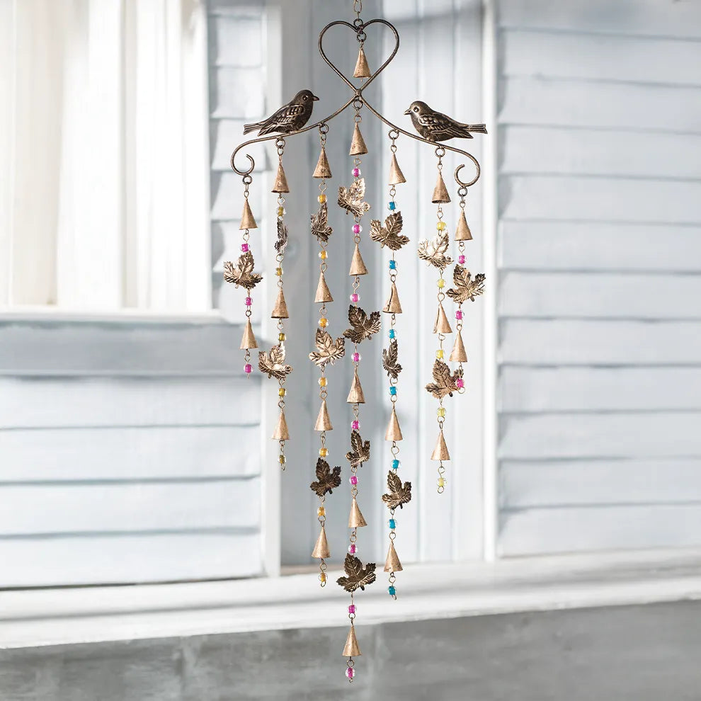 Decorative wind chime with birds and beads in front of a window