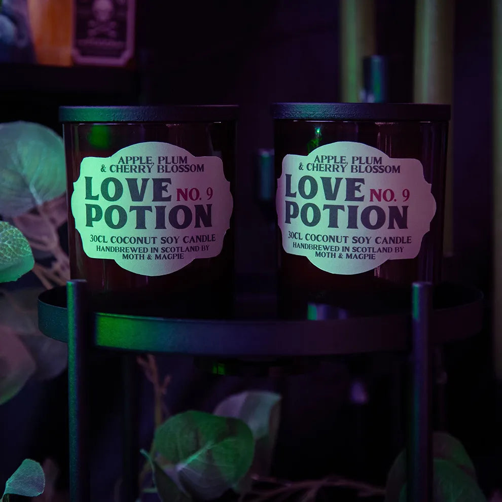 Two 'Love Potion No. 9' candles with glowing labels on a dark background.