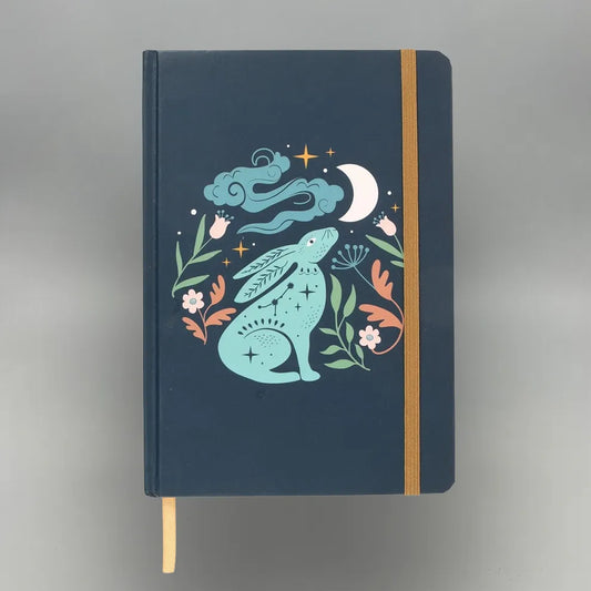 Notebook with a decorative cover featuring a rabbit, moon, and stars on a dark blue background.