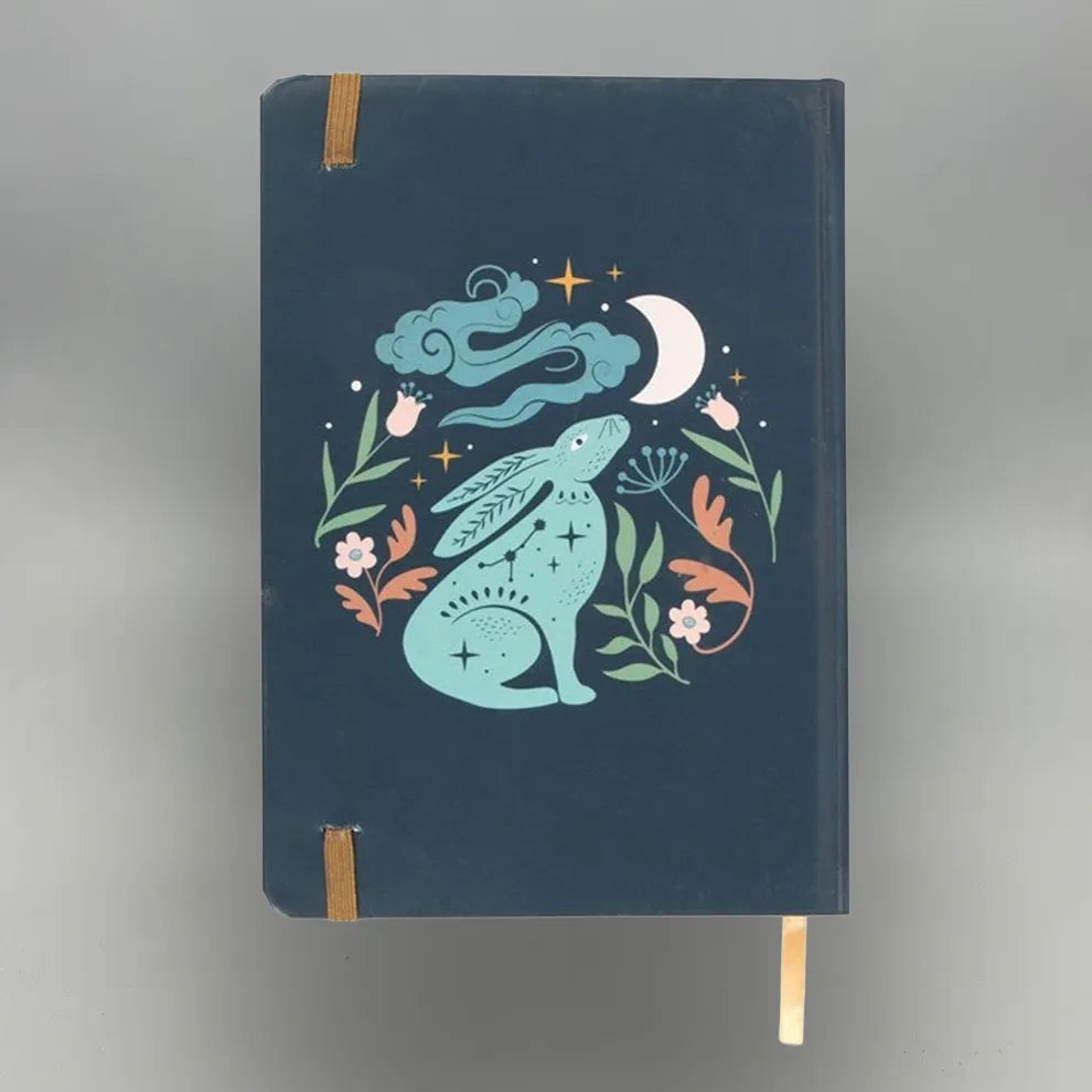 Notebook with a decorative cover featuring a rabbit, moon, and flowers on a dark blue background.
