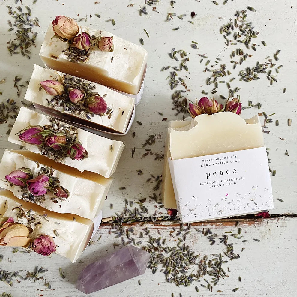 Handcrafted Luxury Hand Made Soap bars with dried flowers and a 'peace' label on a rustic surface with lavender.