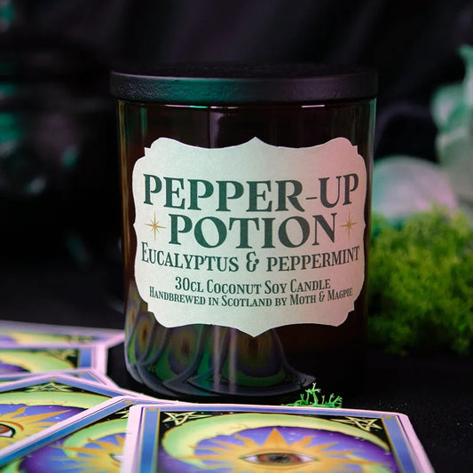 Candle labeled 'Pepper-Up Potion' with tarot cards and greenery in the background