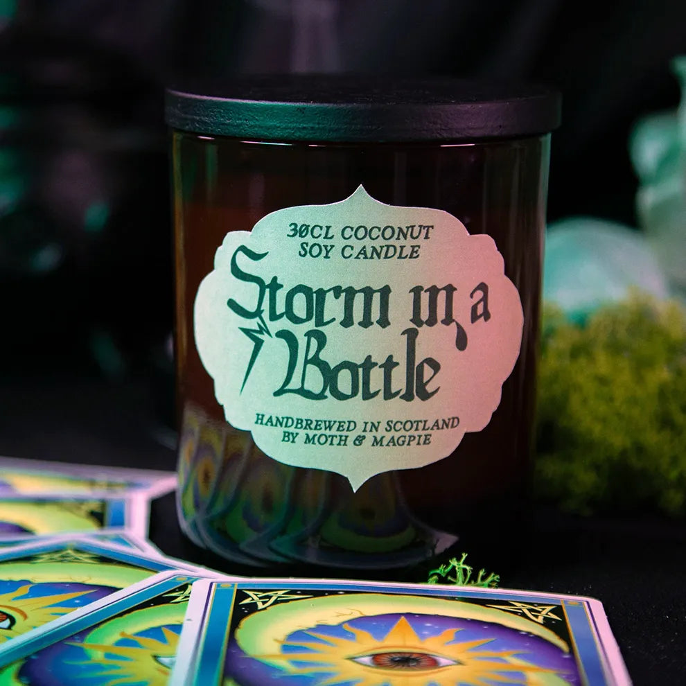 Candle labeled 'Storm in a Bottle' with tarot cards in the foreground
