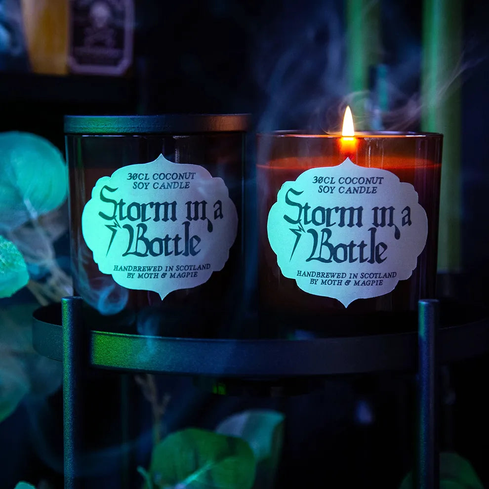 Two 'Storm in a Bottle' candles lit with a dark, mystical background.