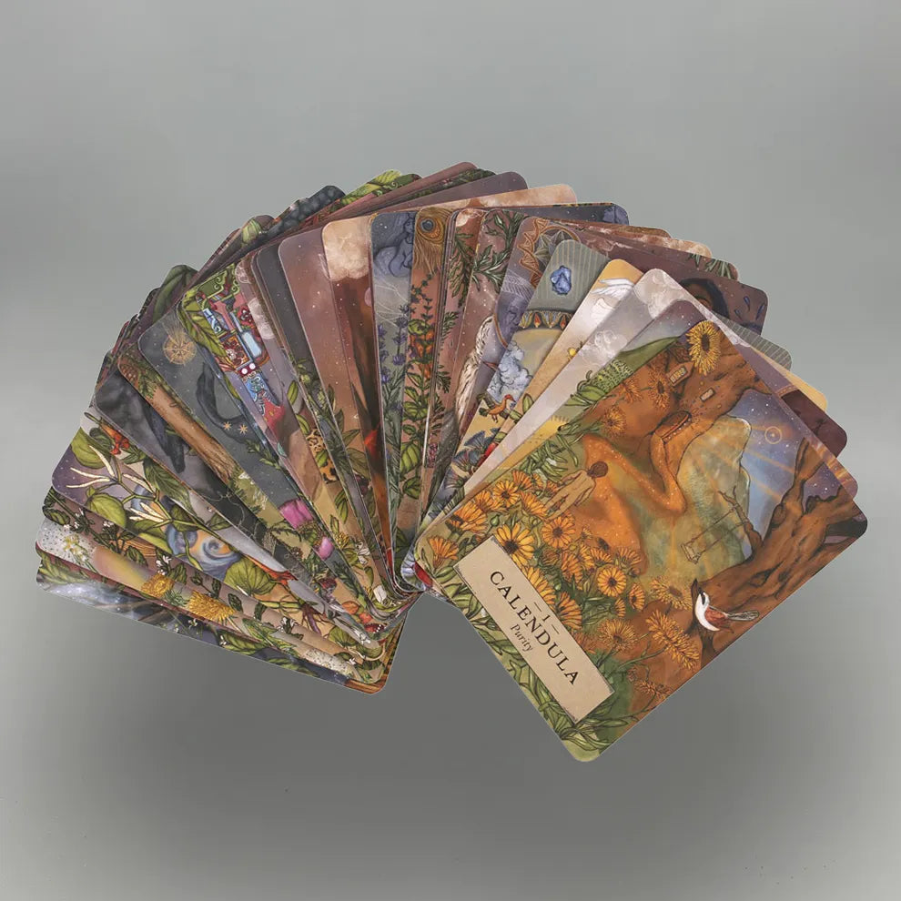 Fanned-out deck of 'The Herbal Astrology Oracle' cards on a gray background