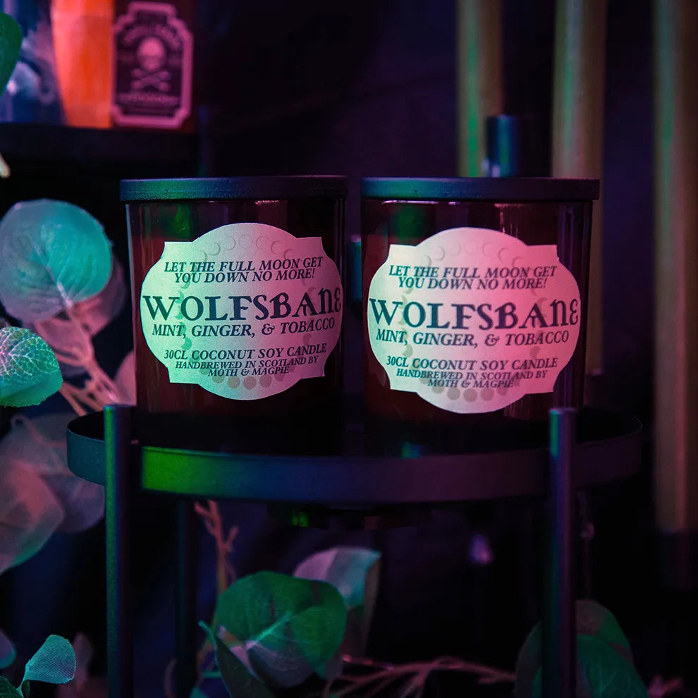Two Wolfsbane candles on a stand with colorful background